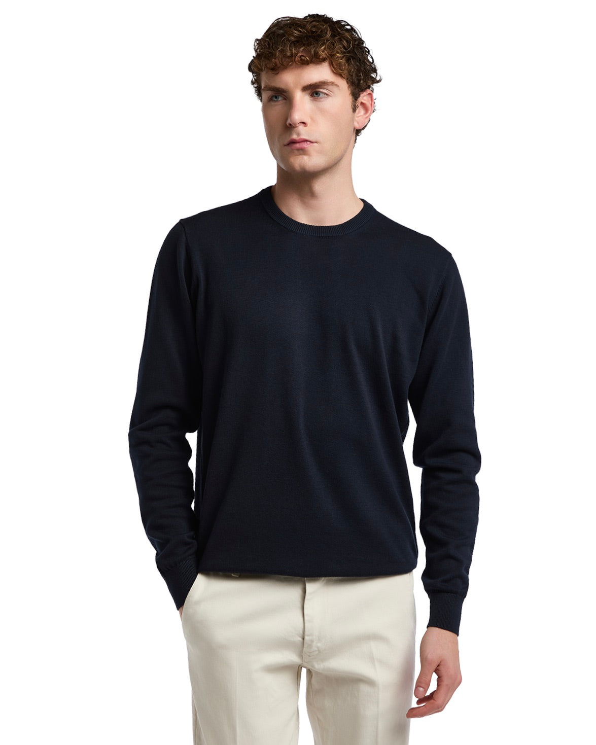 Navy blue crewneck sweater in soft knit fabric, featuring long sleeves and a classic fit, paired with cream trousers.